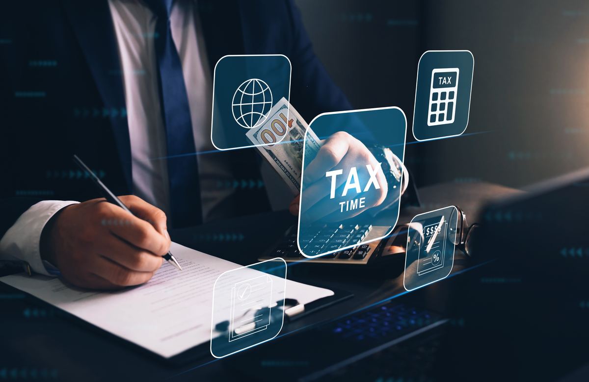 A person signing documents with tax icons overlaid